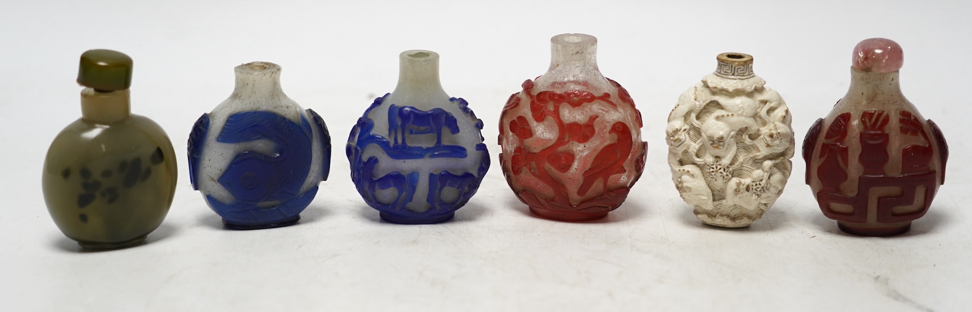 Six Chinese snuff bottles including a moulded and white glazed ‘Buddhist lion’ snuff bottle, 19th century, three overlaid glass snuff bottles and two glass snuff bottles (6)